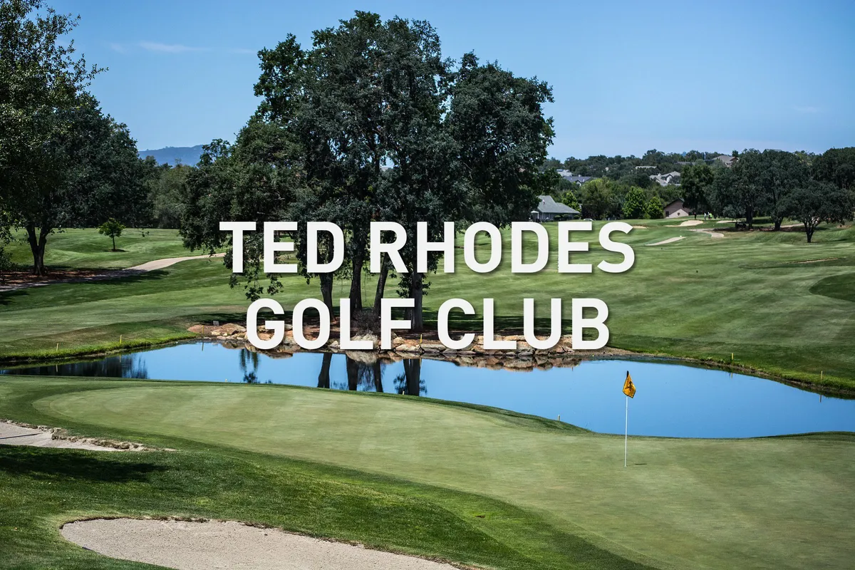 A scenic view of a golf green bordered by a reflective pond and trees, with a golf flag marking the hole. The image captures leisure, relaxation, and social opportunities for families at Ted Rhodes Golf Club.