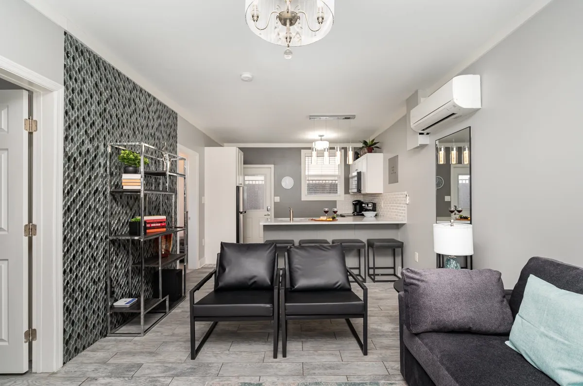 A modern interior with a chic seating arrangement, a striking chandelier, and a textured accent wall. The open layout naturally encourages social gatherings, mingling, and easy interaction between guests.